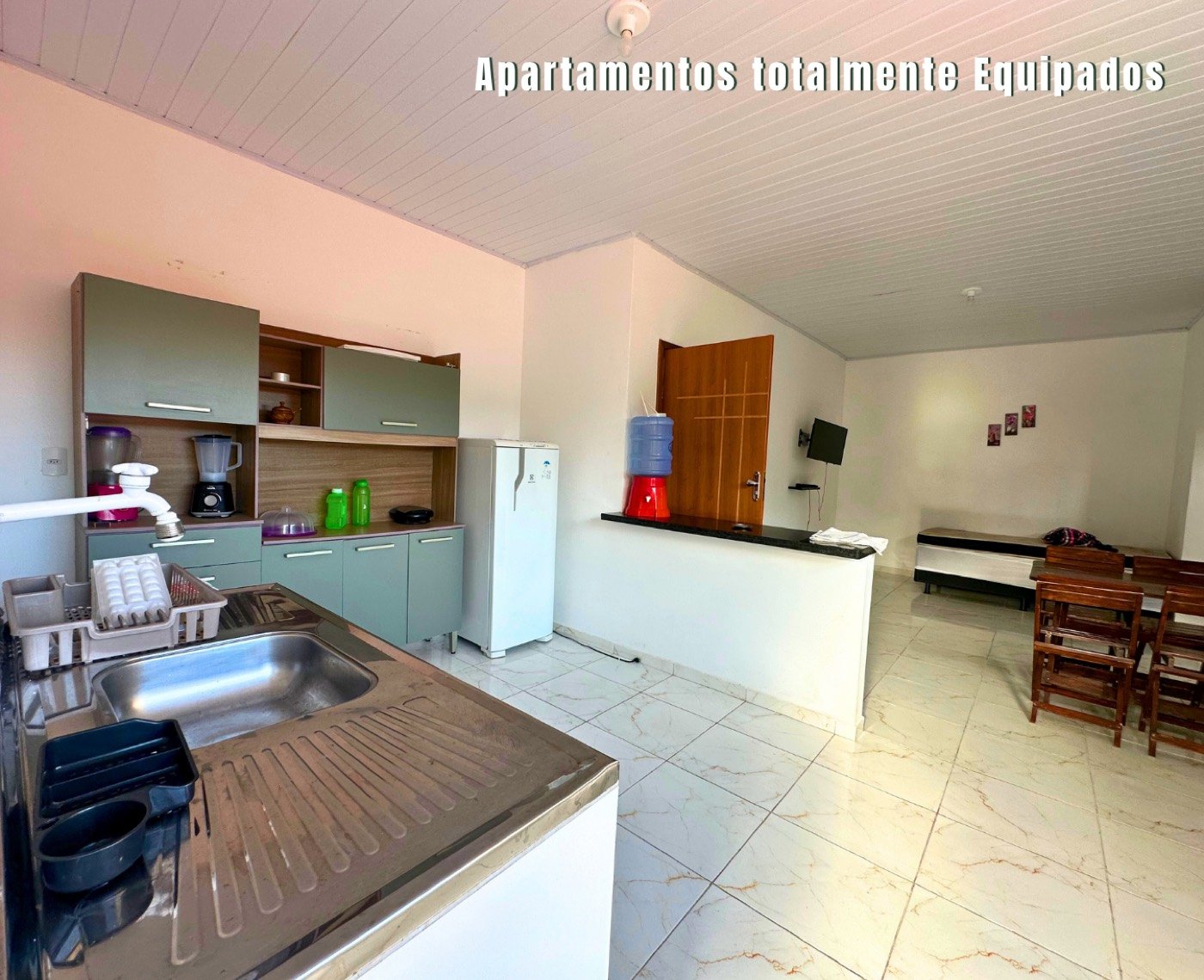 Cozinha equipada com geladeira, armários e pia no apartamento de temporada