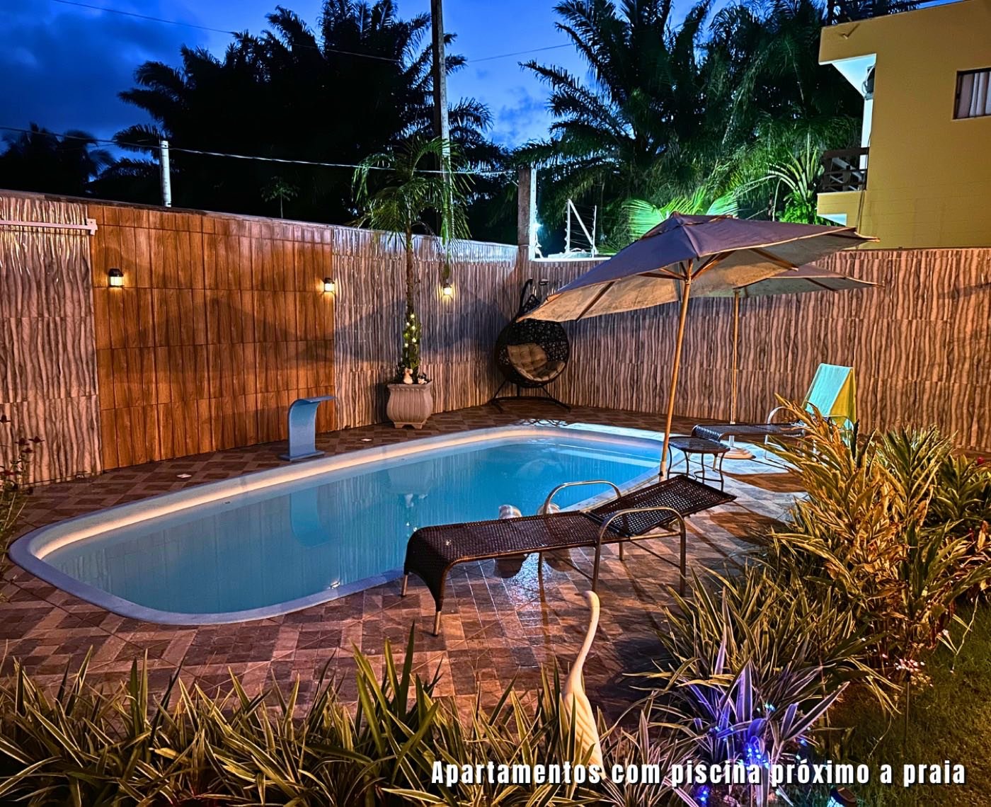 Piscina da Kitnet Noeli iluminada ao anoitecer em Olivença